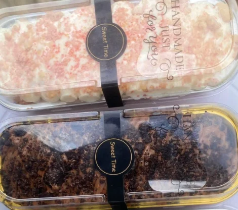 Two of her mini cakes in long clear boxes printed 'Handmade just for you'